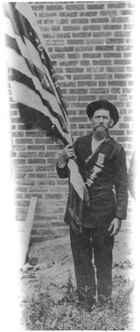 Unidentified bearded man wearing veterans’ reunion badges and holding a flag
